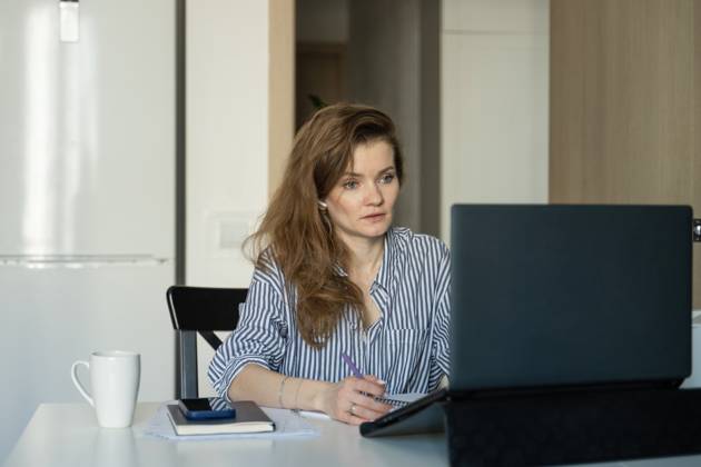 MR_ID27929_20617_TatyanaRangulova.jpg, PR_ID27929_10891_Cat.jpg, PR_ID27929_10892_Room.jpg Woman in striped shirt works at home, focused on laptop. She writes in a notebook with a cup on the table, symbolizing work-from-home productivity., Property released Model Released LiliyaSolopova_ID27929_802069_012 Copyright: xLiliyaxSolopovax