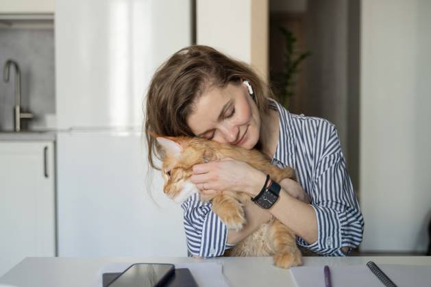 MR_ID27929_20617_TatyanaRangulova.jpg, PR_ID27929_10891_Cat.jpg, PR_ID27929_10892_Room.jpg A woman embraces a ginger cat while sitting at a table in a cozy kitchen. She wears striped clothing and earbuds, exuding warmth and contentment in a relaxing home environment., Property released Model Released LiliyaSolopova_ID27929_802076_016 Copyright: xLiliyaxSolopovax