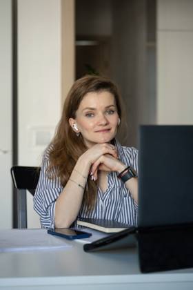 MR_ID27929_20617_TatyanaRangulova.jpg, PR_ID27929_10891_Cat.jpg, PR_ID27929_10892_Room.jpg A woman in a striped shirt sits at a table with a laptop, phone, and notebook, smiling and listening with earbuds. Cozy home setting implies comfort and relaxation., Property released Model Released LiliyaSolopova_ID27929_802081_020 Copyright: xLiliyaxSolopovax