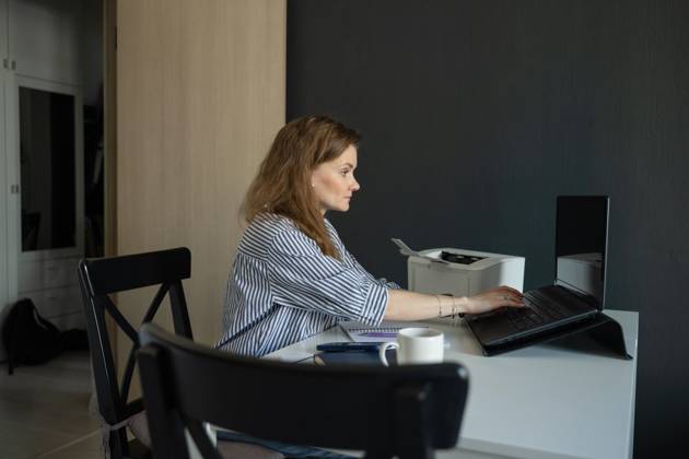 MR_ID27929_20617_TatyanaRangulova.jpg, PR_ID27929_10891_Cat.jpg, PR_ID27929_10892_Room.jpg A woman focuses on her laptop in a home office, seated at a desk with a modern printer, notebook, and mug. The setting creates a productive and comfortable workspace., Property released Model Released LiliyaSolopova_ID27929_802086_024 Copyright: xLiliyaxSolopovax