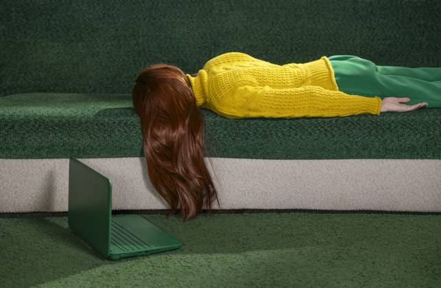 IMAGO Creative, Gesellschaft, Leisure Sickness Red-haired woman lying on a couch at home with a laptop, appearing tired and resting. model released, Symbolfoto, MBLF00807
