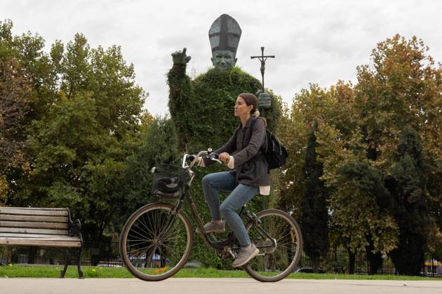 April 23, 2025, Santiago, Metropolitana, Chile: A woman cycles past the statue of Pope John Paul II in Santiago, Chile, days after the death of Pope Francis and shortly before his funeral. Santiago Chile - ZUMAb332 20250423_zip_b332_007 Copyright: xMatiasxBasualdox