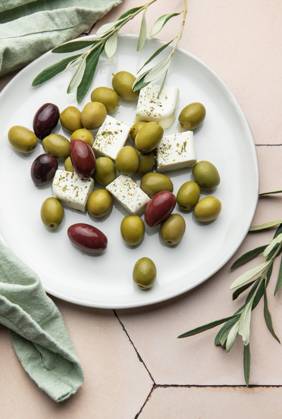Weißer Teller mit grünen und schwarzen Oliven, Fetakäsewürfeln und Olivenzweigen Delicious greek salad with green and black olives, and feta cheese cubes seasoned with oregano, served on a white plate, accompanied by olive branches (License=RF) Copyright: xZoonar.com OlenaxRudox 23386893