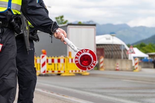 Grenzkontrolle der Bundespolizei an der Kontrollstelle Kiefersfelden, Inntal Ost, an der Autobahn A93 zwischen Deutschland und Österreich. Ein Polizist hält auf der Autobahn eine Polizeikelle mit Aufschrift HALT POLIZEI