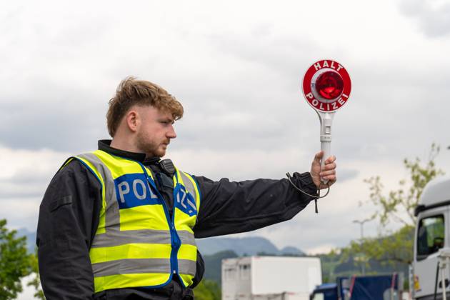Grenzkontrolle der Bundespolizei an der Kontrollstelle Kiefersfelden, Inntal Ost, an der Autobahn A93 zwischen Deutschland und Österreich. Ein Polizist hält auf der Autobahn eine Polizeikelle mit Aufschrift HALT POLIZEI