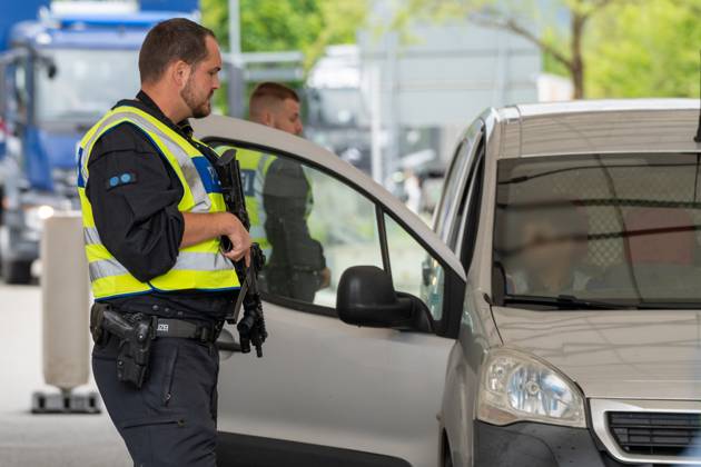 Grenzkontrolle der Bundespolizei an der Kontrollstelle Kiefersfelden, Inntal Ost, an der Autobahn A93 zwischen Deutschland und Österreich. Polizeibeamter mit Maschinengewehr steht vor einer laufenden Kontrolle an der Grenzkontrollstelle
