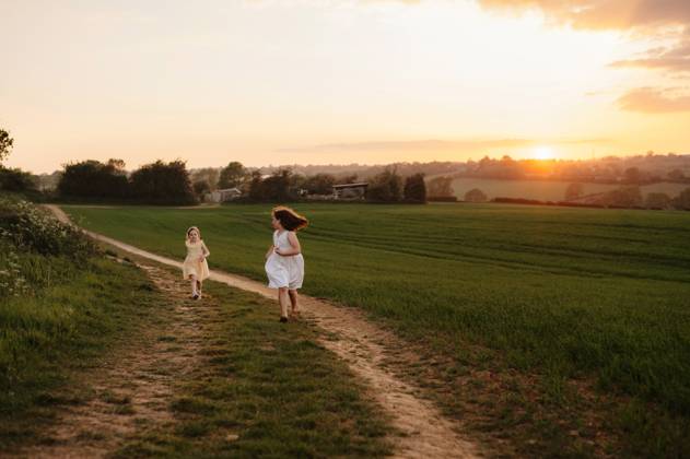 IMAGO Creative, Jahreszeit Sommer, Sommerferien Two young sisters running along a narrow country path at sunset. Corby, England, United Kingdom CR_JNDO250602-1745310-01 ,model released, Symbolfoto