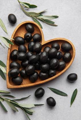 Fresh black olives in heart shaped wooden bowl on gray background with olive branches and copy space Model Released OlenaRudo_ID28871_858125_066 Copyright: xOlenaxRudox RECORD DATE NOT STATED