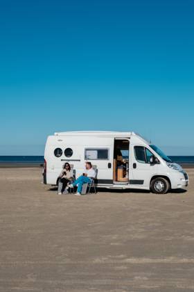 Entspannen am Strand in Dänemark mit einem Wohnmobil an einem sonnigen Tag A couple enjoys a peaceful day at a beach in Denmark, lounging outside their camper van. The clear blue sky enhances their relaxing atmosphere as they savor the tranquil surroundings. (License=RF) ,model released, Symbolfoto Copyright: xZoonar.com FokkexBaarssenx 23681347 ,model released, Symbolfoto ,property released