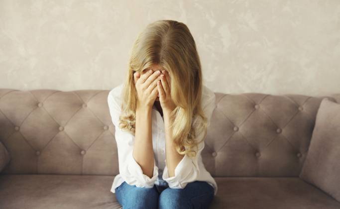 Aufgewühlte, traurige, weinende Frau, die ihre Augen und ihr Gesicht mit den Händen bedeckt, während sie seelisches oder körperliches Leid erfährt, Müdigkeit, die auf der Couch in einem Zimmer zu Hause sitzt Upset sad crying woman covering her eyes and face with her hands while experiencing mental or physical suffering, fatigue sitting on the couch in room at home Copyright: imageBROKER VeronikaxKorneva ibxiqx14270543.jpg ,model released, Symbolfoto ,property released