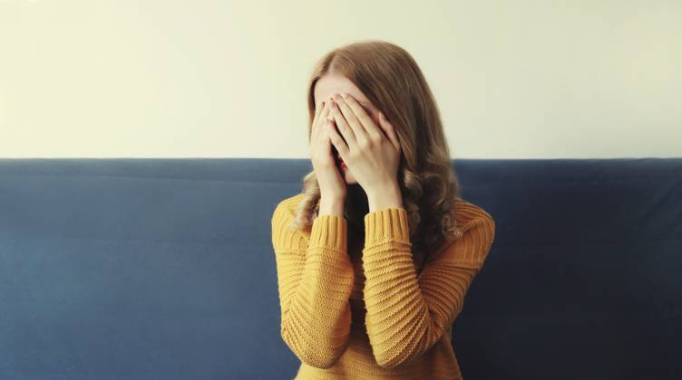 Aufgewühlte, traurige, weinende Frau, die ihre Augen und ihr Gesicht mit den Händen bedeckt, während sie seelisches Leid, Depression und Müdigkeit empfindet, während sie zu Hause auf der Couch sitzt Upset sad crying woman covering her eyes and face with her hands while experiencing mental suffering, depression, fatigue sitting on the couch in room at home Copyright: imageBROKER VeronikaxKorneva ibxiqx14270550.jpg ,model released, Symbolfoto ,property released