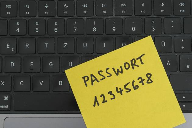 Sicherheitsrisiko auf dem Schreibtisch: Ein Zettel mit dem unsicheren Passwort 12345678 liegt offen auf einem Laptop, ein klassisches Beispiel für fahrlässigen Umgang mit sensiblen Zugangsdaten.
