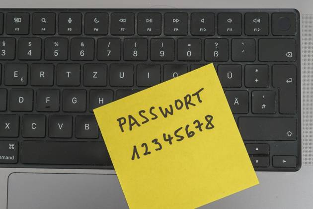 Sicherheitsrisiko auf dem Schreibtisch: Ein Zettel mit dem unsicheren Passwort 12345678 liegt offen auf einem Laptop, ein klassisches Beispiel für fahrlässigen Umgang mit sensiblen Zugangsdaten.