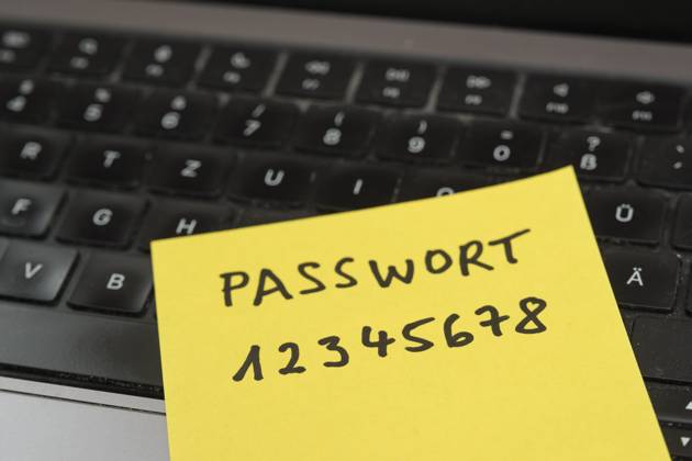 Sicherheitsrisiko auf dem Schreibtisch: Ein Zettel mit dem unsicheren Passwort 12345678 liegt offen auf einem Laptop, ein klassisches Beispiel für fahrlässigen Umgang mit sensiblen Zugangsdaten.