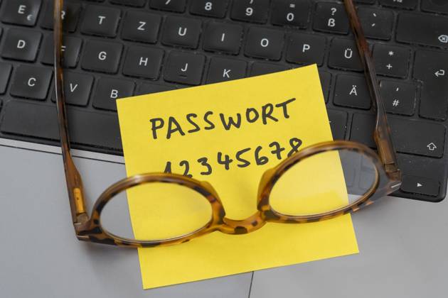 Sicherheitsrisiko auf dem Schreibtisch: Ein Zettel mit dem unsicheren Passwort 12345678 liegt offen auf einem Laptop, ein klassisches Beispiel für fahrlässigen Umgang mit sensiblen Zugangsdaten.