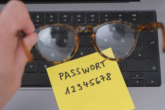 Sicherheitsrisiko auf dem Schreibtisch: Ein Zettel mit dem unsicheren Passwort 12345678 liegt offen auf einem Laptop, ein klassisches Beispiel für fahrlässigen Umgang mit sensiblen Zugangsdaten.