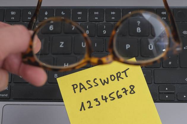 Sicherheitsrisiko auf dem Schreibtisch: Ein Zettel mit dem unsicheren Passwort 12345678 liegt offen auf einem Laptop, ein klassisches Beispiel für fahrlässigen Umgang mit sensiblen Zugangsdaten.