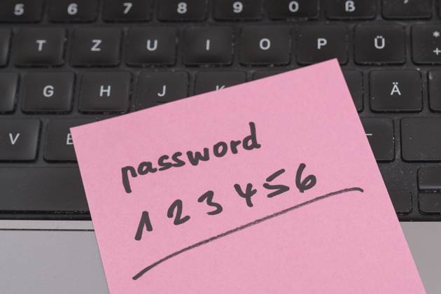 Sicherheitsrisiko auf dem Schreibtisch: Ein Zettel mit dem unsicheren Passwort 123456 liegt offen auf einem Laptop, ein klassisches Beispiel für fahrlässigen Umgang mit sensiblen Zugangsdaten.