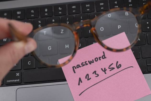 Sicherheitsrisiko auf dem Schreibtisch: Ein Zettel mit dem unsicheren Passwort 123456 liegt offen auf einem Laptop, ein klassisches Beispiel für fahrlässigen Umgang mit sensiblen Zugangsdaten.