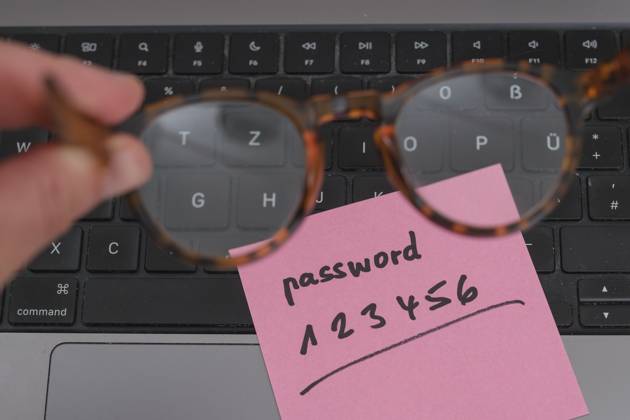 Sicherheitsrisiko auf dem Schreibtisch: Ein Zettel mit dem unsicheren Passwort 123456 liegt offen auf einem Laptop, ein klassisches Beispiel für fahrlässigen Umgang mit sensiblen Zugangsdaten.
