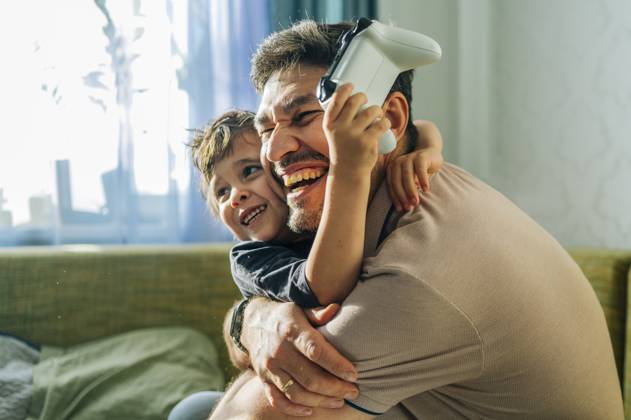 IMAGO Creative, Lifestyle, Gaming Smiling father and child playing console game together at home model released, Symbolfoto property released, ANAF04839