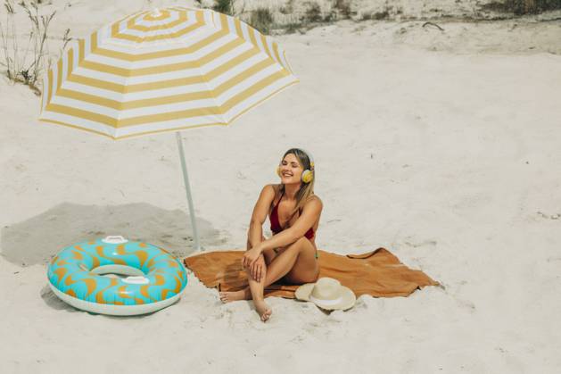 Brunette relaxing on sandy beach under umbrella with inflatable ring model released, Symbolfoto, VSNF03672