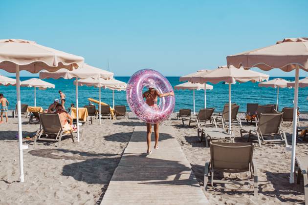 Rear view of girl walking to the beach with swim ring. summer beach holiday. Rear view of girl walking to the beach with swim ring in hand. Summer beach holiday. model released