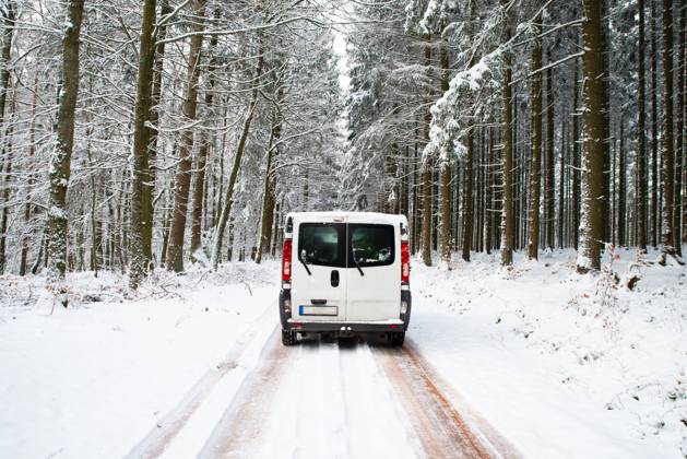 Wohnmobil auf einer Straße durch einen schneebedeckten Wald im Winter, Abenteuerurlaub und Lebensstil in den Wäldern, rutschige Autobahn