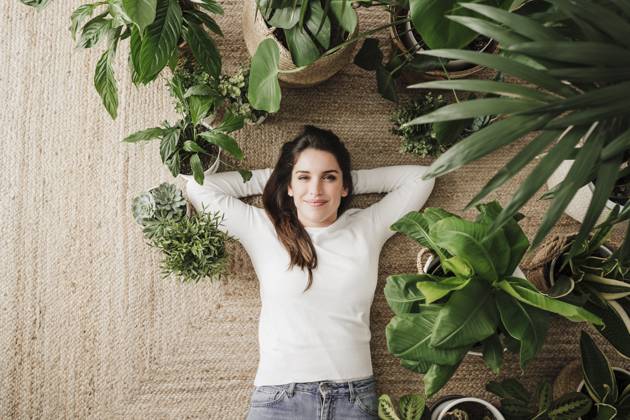 Smiling woman with hands behind head relaxing on carpet amidst plants model released, Symbolfoto property released, EBBF08159