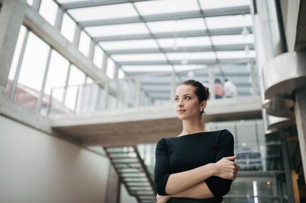 Portrait of young businesswoman standing in modern openspace office building. Portrait of young businesswoman standing in modern openspace office building. Low angle view. model released