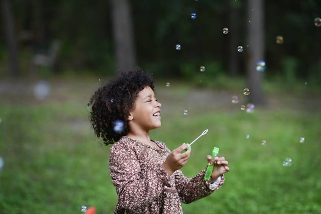 Laughing girl blows bubbles in grassy outdoor area. United States, Florida, Floral City CR_YWQX250910A-1811574-01 ,model released, Symbolfoto
