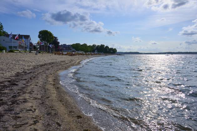 Sandstrand mit welligem Meer unter blauem Himmel, die Sonne reflektiert auf dem Wasser, Heikendorf, Kreis Plön, Kieler Förde, Schleswig-Holstein Sandy beach beach with undulating sea under a blue sky, the sun reflected on the water, Heikendorf, Plön district, Kiel Fjord, Schleswig-Holstein Copyright: imageBROKER RaimundxLinke ibxrde15149785.jpg