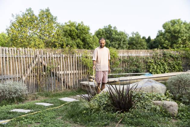 Man watering xerophytic plants in eco-friendly backyard garden model released, Symbolfoto property released, PCLF02598