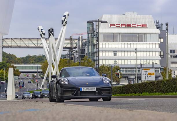 Porscheplatz, Stuttgart Zuffenhausen mit Porsche Hauptverwaltung. Kunstwerk Inspiration 911 von Gerry Judah: drei Stelen, die in bis zu 24 Metern Höhe je einen Porsche 911 präsentieren. Autotransporter mit Neuwagen. 29.09.2025: Stuttgart, Baden-Württemberg, Deutschland