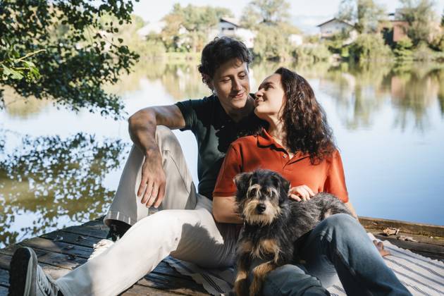 Couple with dog relaxing together outdoors by a lakeside in nature model released, Symbolfoto property released, NDEF02878