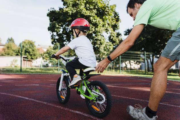 Father supporting son learning to ride bicycle outdoors model released, Symbolfoto, NDEF02934