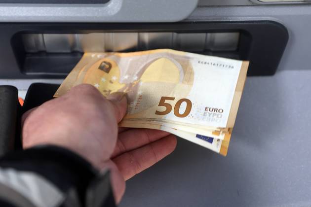 Bargeldversorgung aus einem Automat Eine Person holt an einem Geldautomaten eine größere Menge Bargeld in 50 Euro Geldscheinen ab