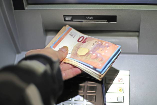 Bargeldversorgung aus einem Automat Eine Person holt an einem Geldautomaten Bargeld ab