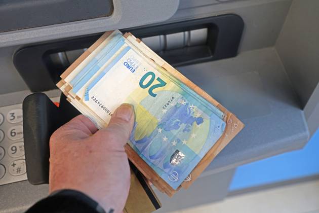 Bargeldversorgung aus einem Automat Eine Person holt an einem Geldautomaten eine größere Menge Bargeld ab.