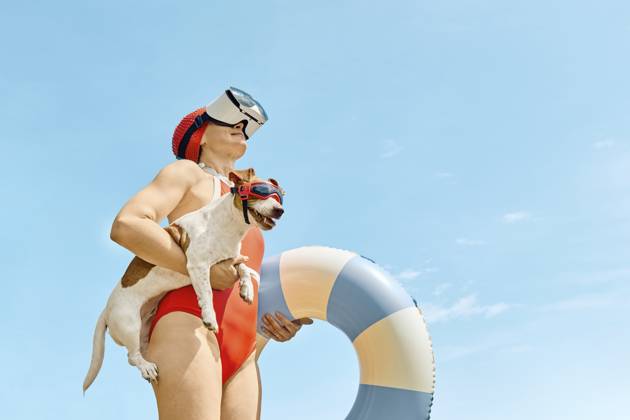 Woman in red swimsuit with virtual reality glasses holding a Jack Russell Terrier and a swimming ring outdoors model released, Symbolfoto property released, CATF00646