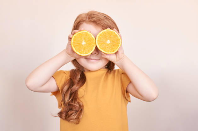 Kaukasisches Kind mit roten Haaren, die die Augen mit orangefarbenen Scheiben bedecken, in verspielter Pose auf beigem Hintergrund Caucasian child with red hair covering eyes with orange slices in playful pose on beige background. (License=RF) ,model released, Symbolfoto Copyright: xZoonar.com ElenaxSafonovax 24340219 ,model released, Symbolfoto ,property released