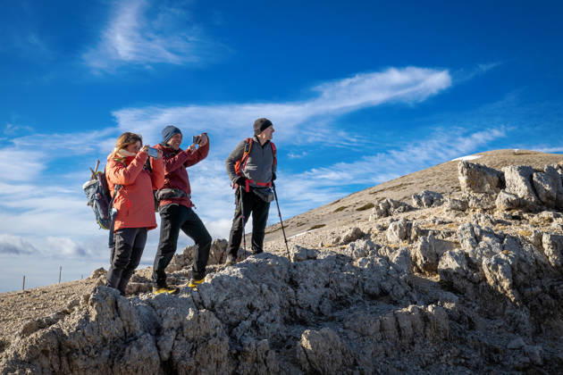 Hikers on a mountain trail. Guarcino (FR), Italy - December 21, 2025: Three hikers on a rocky mountain peak enjoy photographing the surrounding landscape with their smartphones. Guarcino FR Italy Copyright: xGennaroxLeonardix