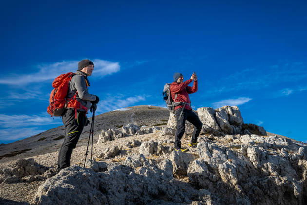 Hikers on a mountain trail. Guarcino (FR), Italy - December 21, 2025: Two hikers on a rocky mountaintop observe the surrounding landscape and one of them photographs it with his smartphone. Guarcino FR Italy Copyright: xGennaroxLeonardix