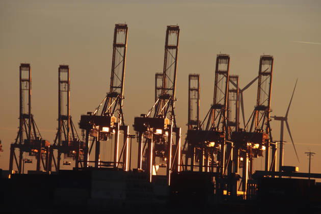 Containerbrücken im Hamburger Hafen reflektieren das Licht der untergehenden Sonne.