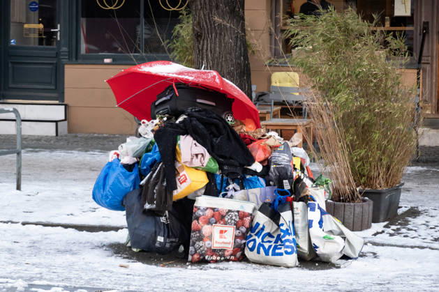 Obdachlos mit einem temporären Obdach aus Regenschirm, Tüten und Einkaufswagen auf der Strasse mitten im Schnee in Berlin am 7. Januar 2026. Alltag in Berlin