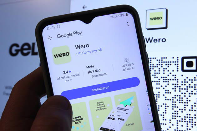 Auf einem Smartphone wurde die App vom Zahlungsdienst Wero bei Google Play aufgerufen worden. Dahinter wurde auf einem Laptop die Website von Wero aufgerufen. Symbolbild Symbolfoto. Schnelsen Hamburg