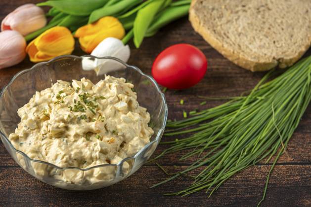Eiersalat in Schüssel mit frischen Kräutern und Brot, dekoriert mit Frühlingsblumen Egg salad in bowl with fresh herbs and bread, decorated with spring flowers Copyright: imageBROKER LucasxSeebacher ibxlse16536832.jpg