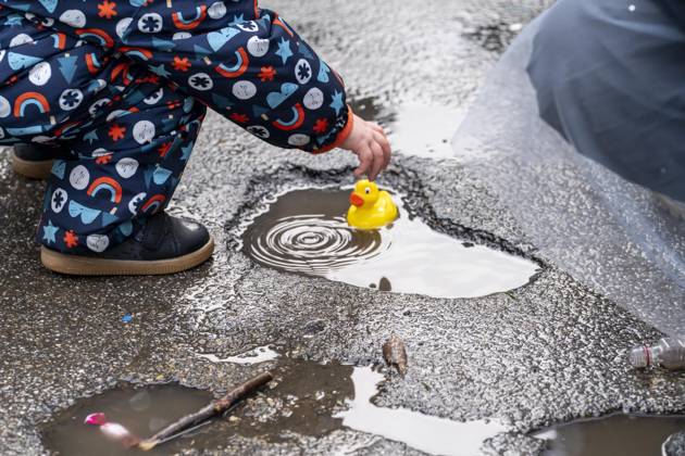 Rosenmontagszug in Düsseldorf, Teilnehmer des Umzugs, Kind spielt mit Plastikentchen, das es beim Zug als Kamelle gefangen hat, machen sich regenfest, beim Strassenkarneval, bei teils starkem Regen, NRW, Deutschland Rosenmontag DUS