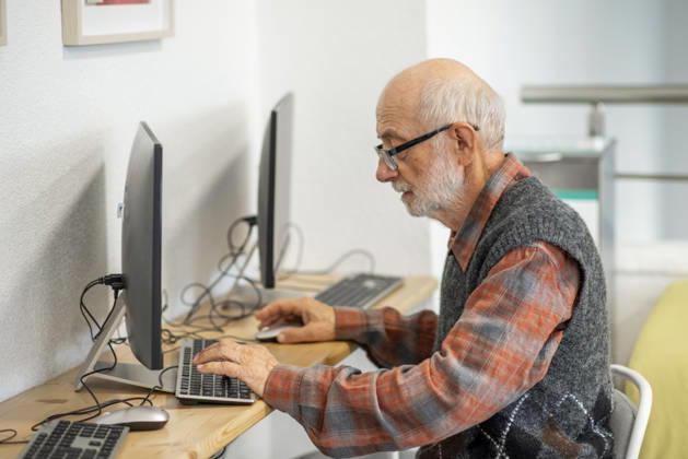 Senior man working on computer at desk. Focused senior man working on computer at desk. model released