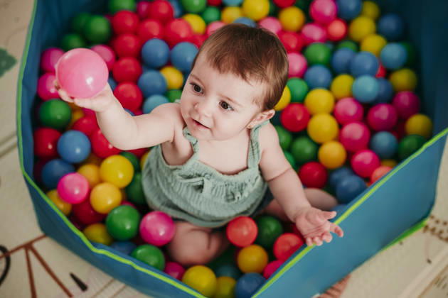 Baby playing with colorful pool balls at home and smiling model released, Symbolfoto property released, EBBF09317